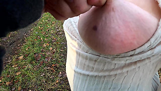 Squeezing her hard naked nipples outdoors